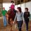 A group of people riding horses in an indoor arena.